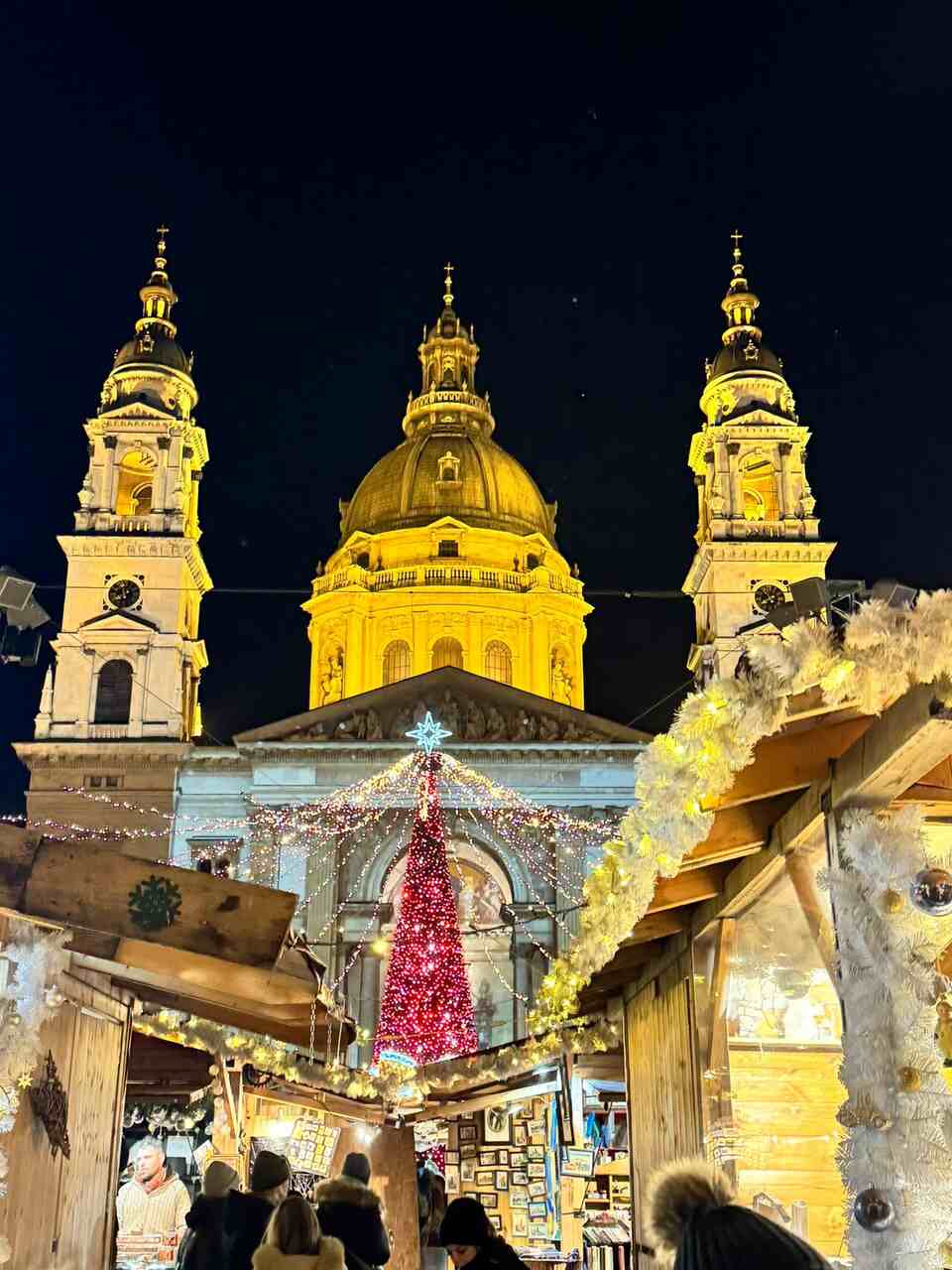 St. Stephen’s Basilica Christmas market in Budapest with red tree, festive stalls and night lights