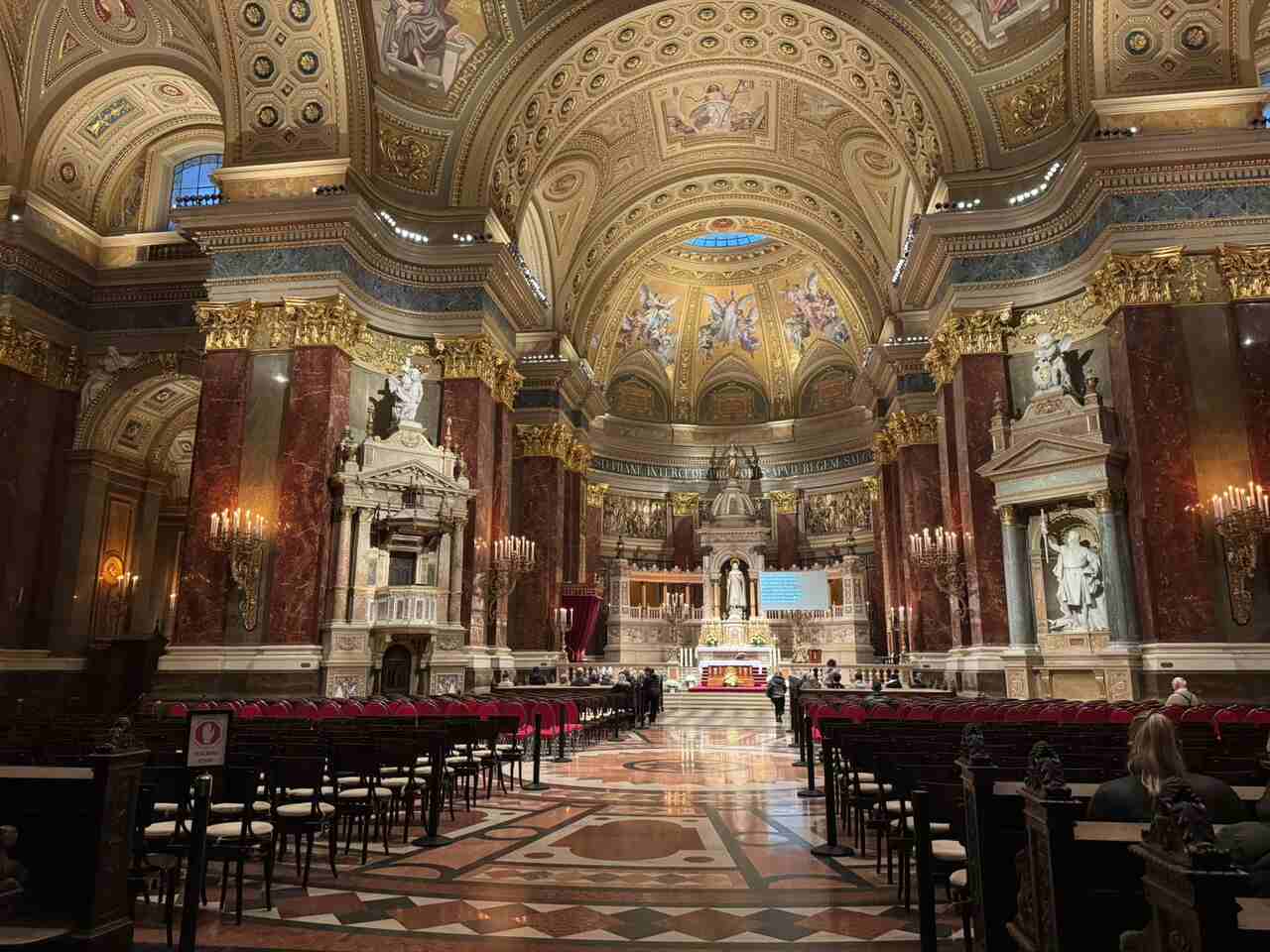 Interior of St Stephen’s Basilica Budapest, showing the ornate nave, marble columns and golden dome above the main altar.
