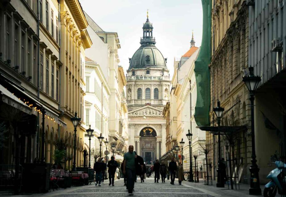 Pedestrian street leading to St Stephen’s Basilica in Budapest, with the dome and main façade framed by historic buildings.