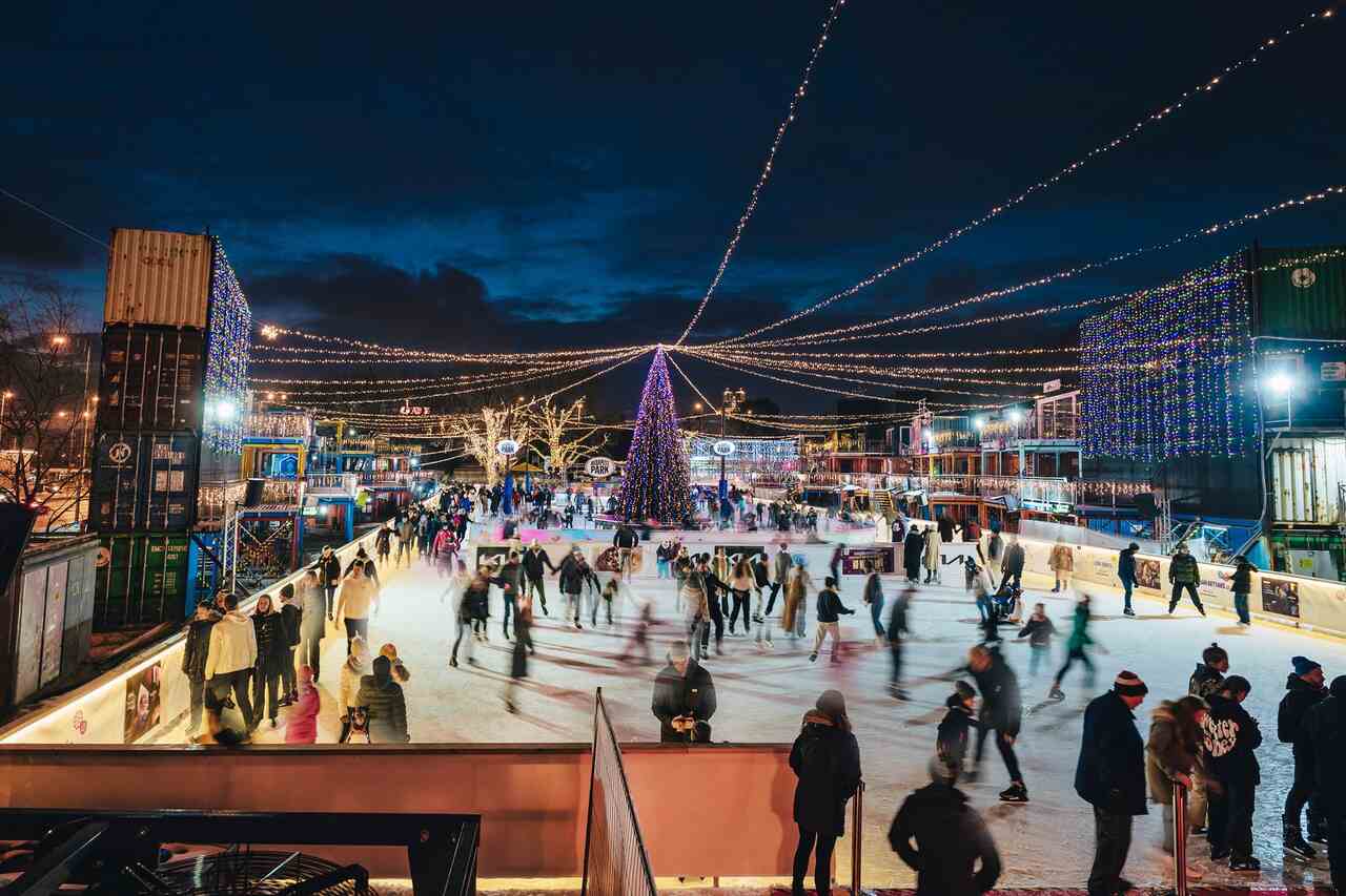 Ice skating at KoriPark in Budapest Park at night, with Christmas lights, a large decorated tree and skaters enjoying the winter rink.