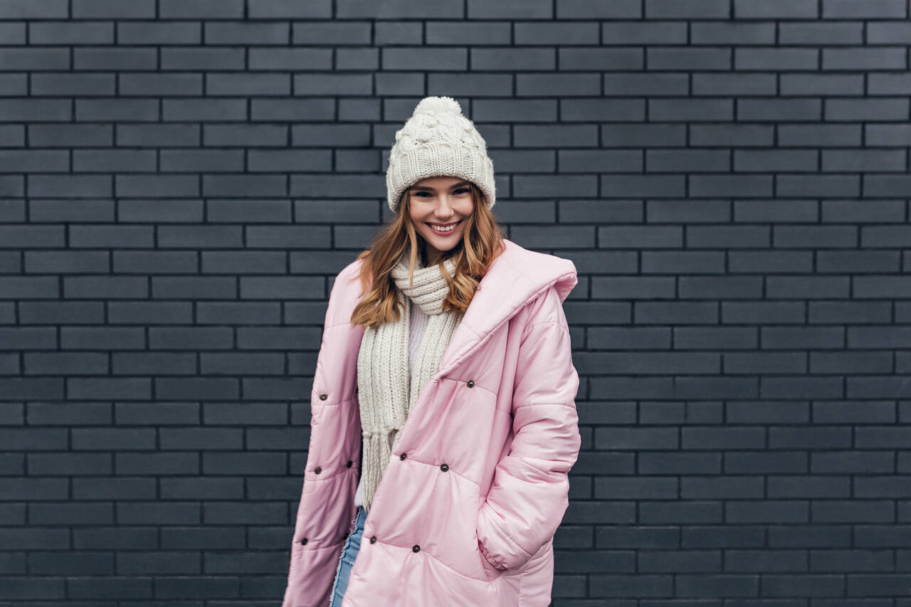Woman in Budapest wearing a pink winter coat, white knit hat, and scarf — example of what to wear in Budapest in winter.