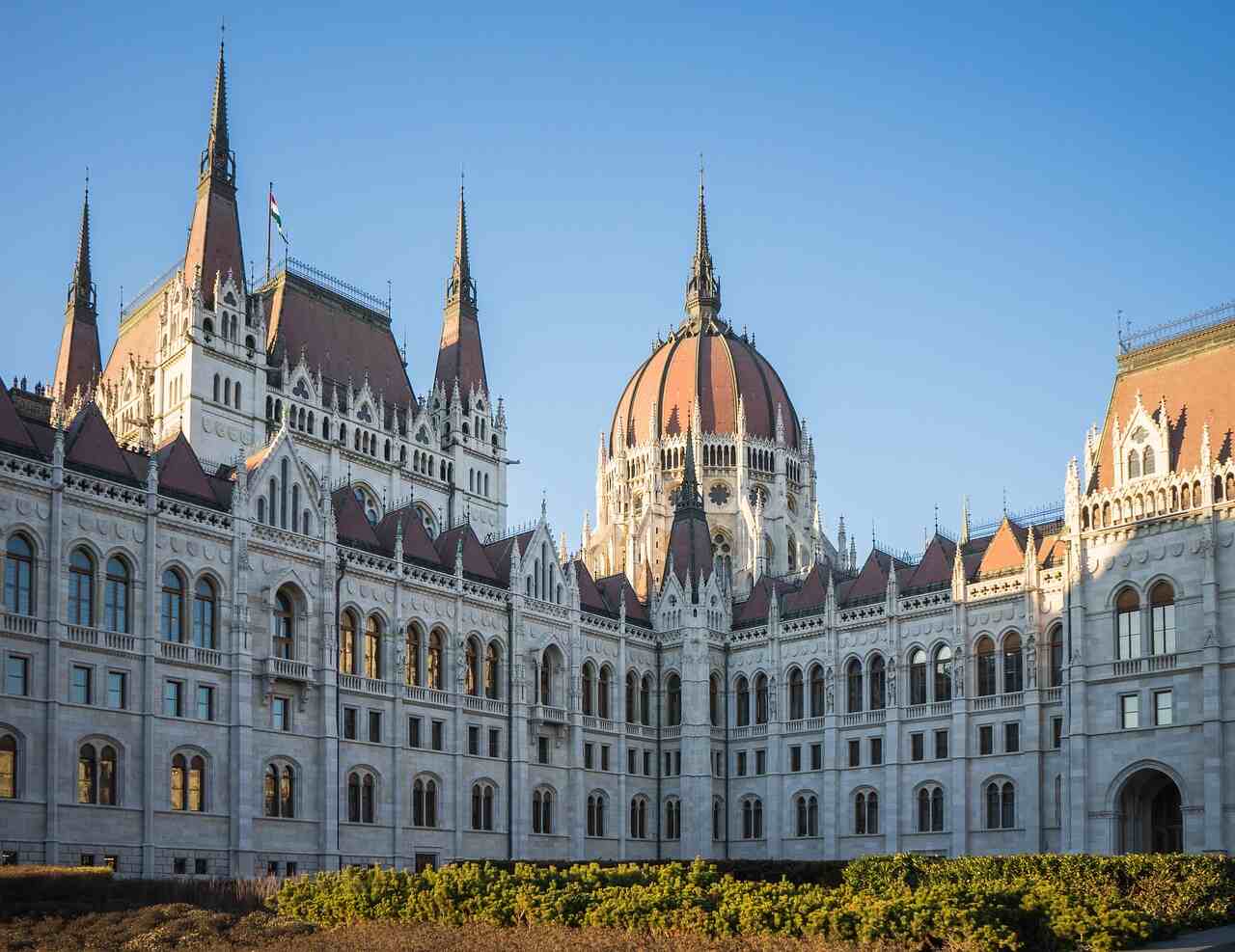 Exterior of the Hungarian Parliament Building in Budapest, showing its Neo-Gothic façade and central dome under clear afternoon light