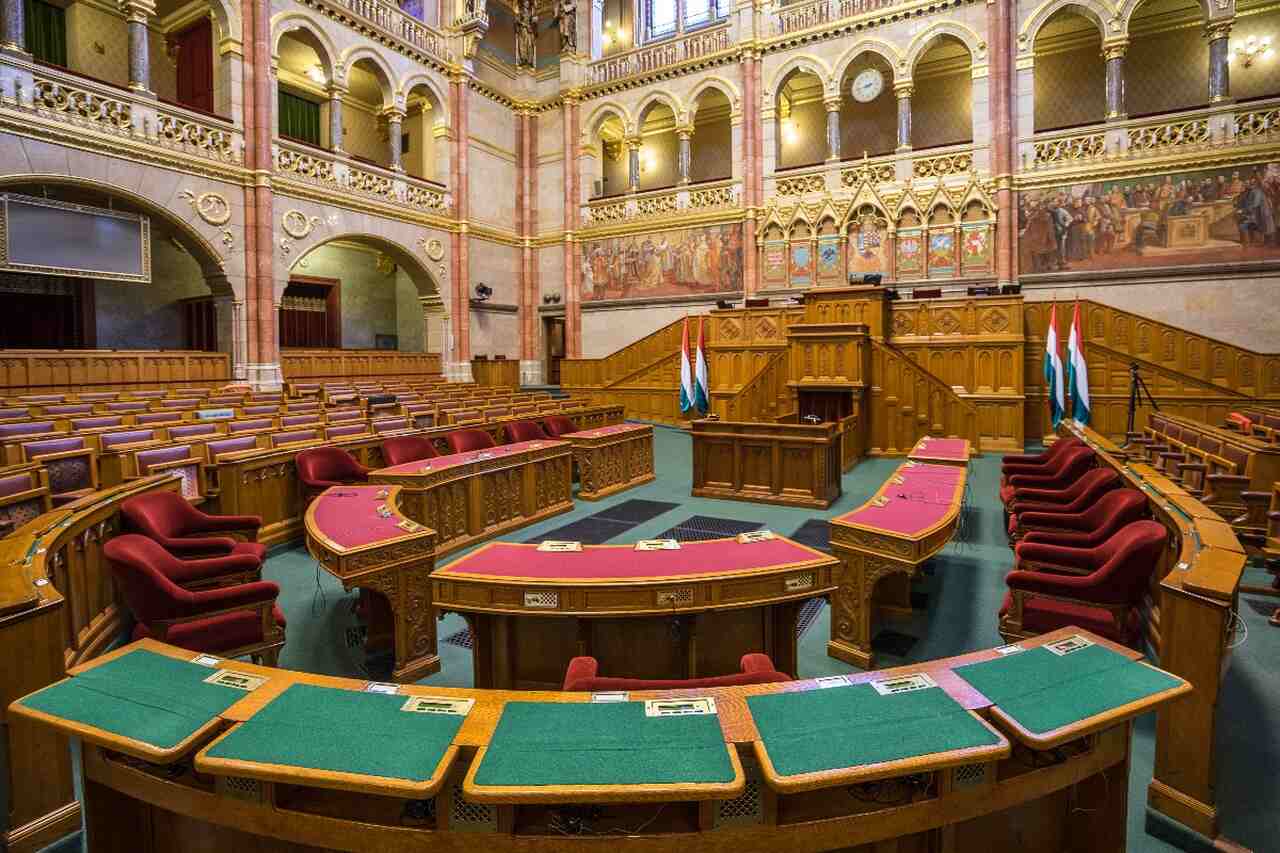 Interior of the Hungarian Parliament Building showing the historic Chamber of Peers, with wooden seats, arches and decorative murals visited during the Parliament tour.