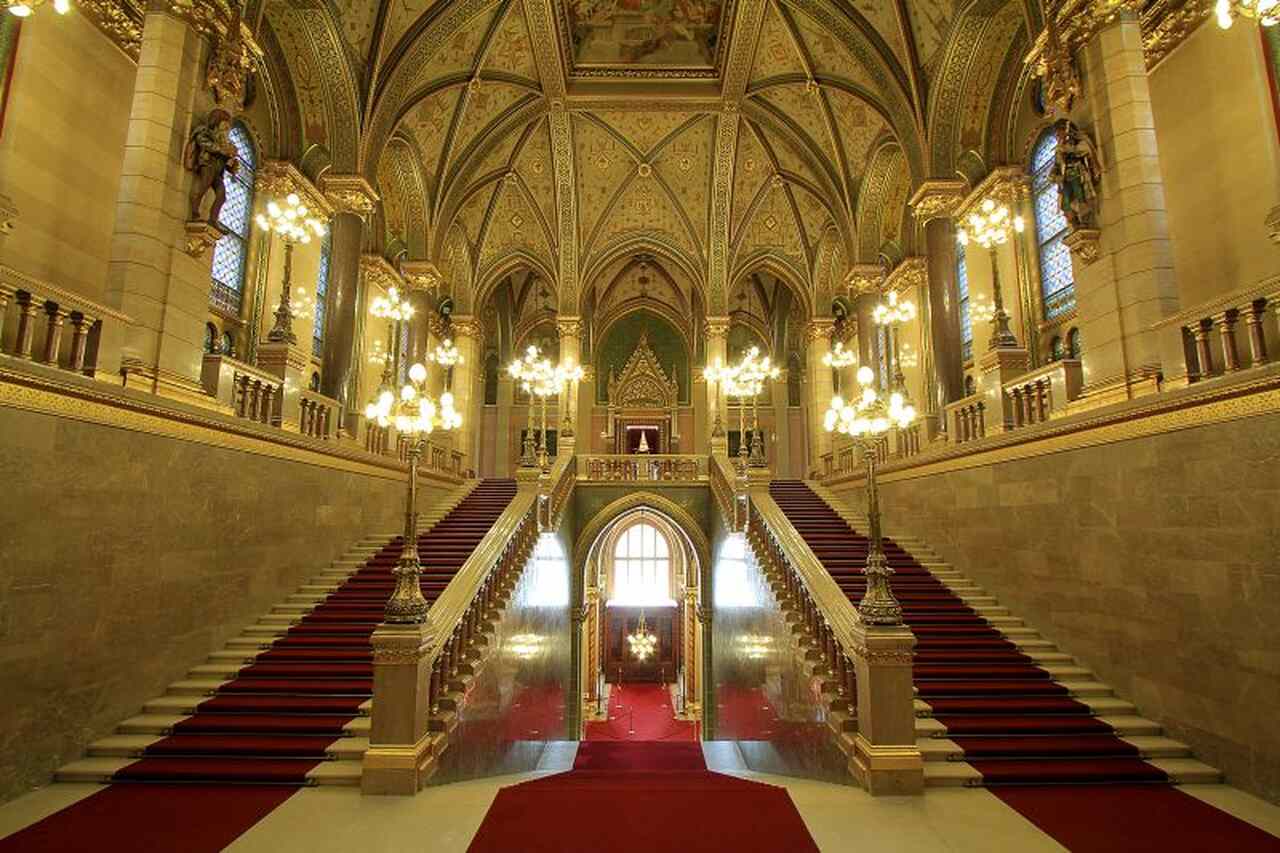Grand Staircase inside the Hungarian Parliament Building during the official tour, with red carpets, gold decorations and ornate vaulted ceilings.