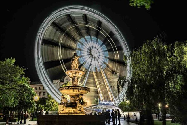 Budapest city center at night with the Ferris wheel and people walking around, showing a lively and safe atmosphere for tourists