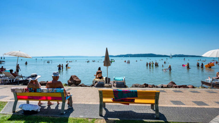 People relaxing by the shore of Lake Balaton on a sunny summer day, representing Hungary’s most popular lake destination.