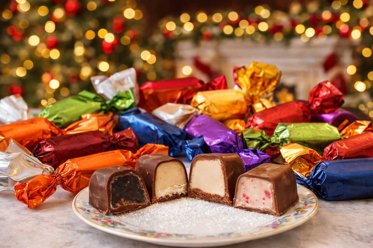 Traditional Hungarian Christmas candies with colorful wrappers, some cut open to show different fillings, displayed on a festive table